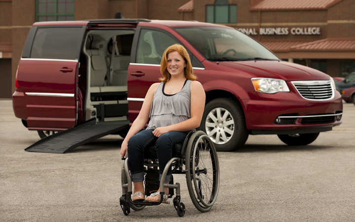 Female wheelchair user poses in front of her wheelchair accessible van.